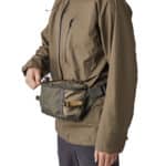 Homme portant une parka marron et un sac banane vert à la taille