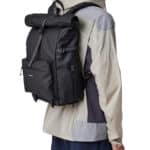 Homme portant une parka de couleur claire et un sac à dos noir vue de dos